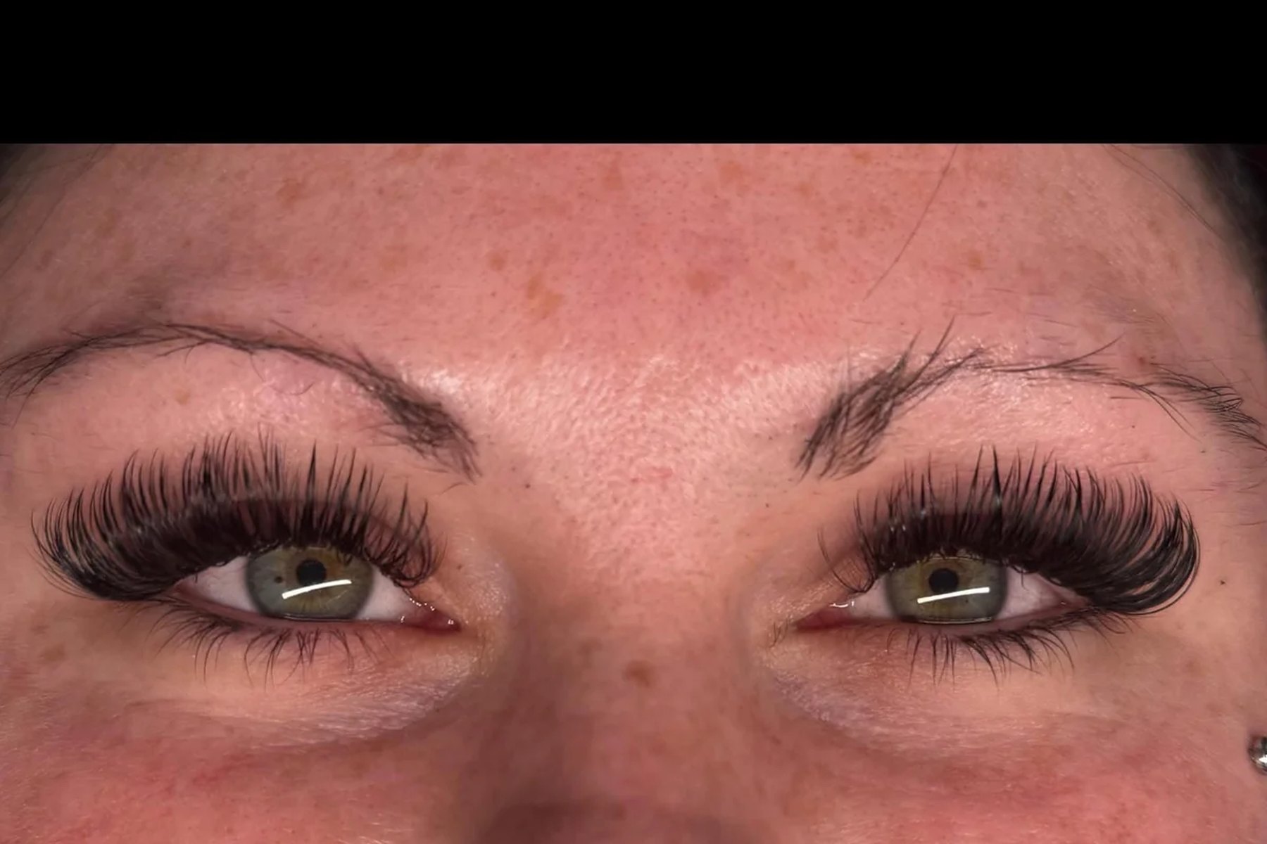 Client lying back with eyes closed during a lash extension application